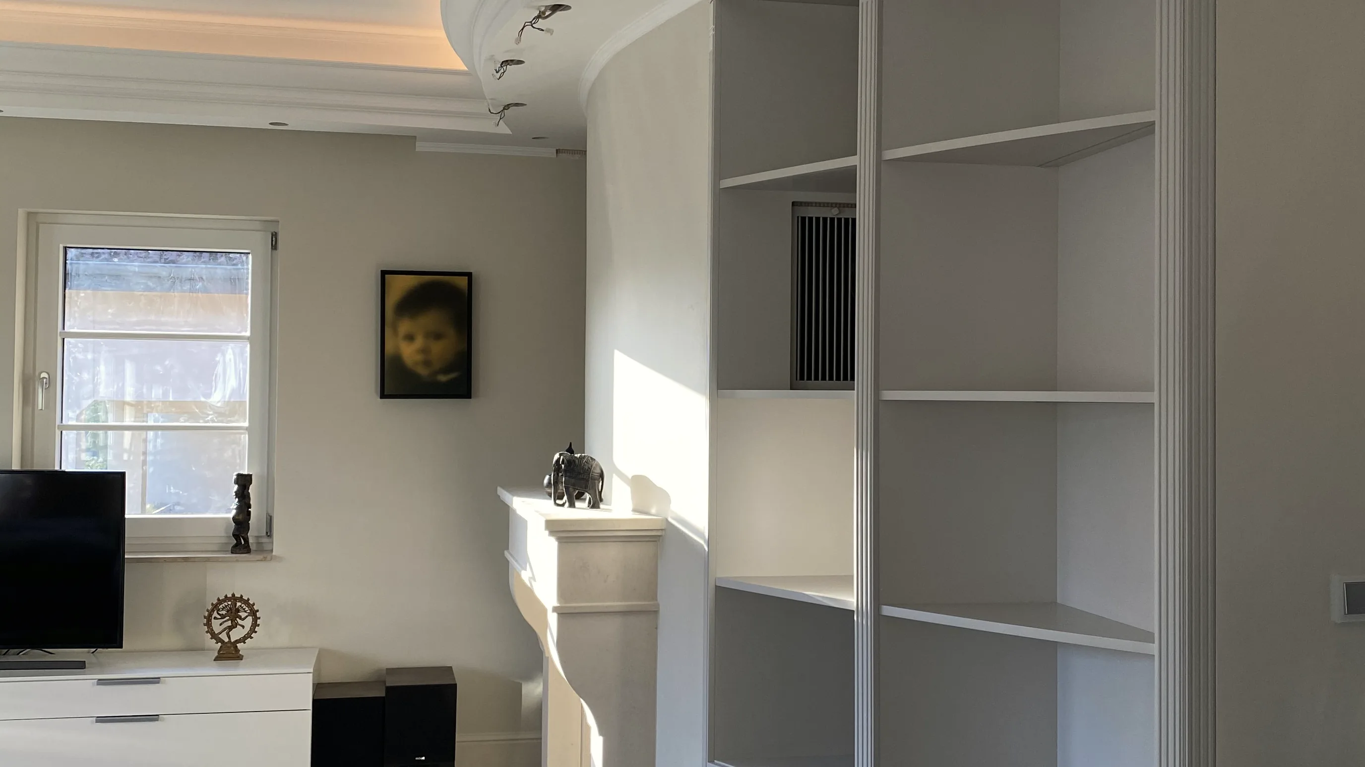 Eckschrank mit Regalen unter der runden Decke, im Vordergrund ein kleiner Teppich und ein dunkler Tisch