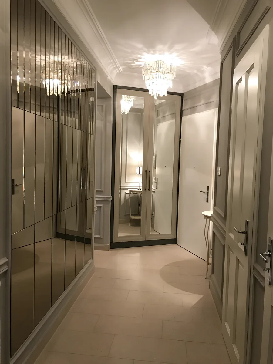 Schmaler Flur mit einem Einbauschrank mit Spiegeltüren in der Ecke, Kristalllüster an der Decke, Konsolentisch und Tür rechts