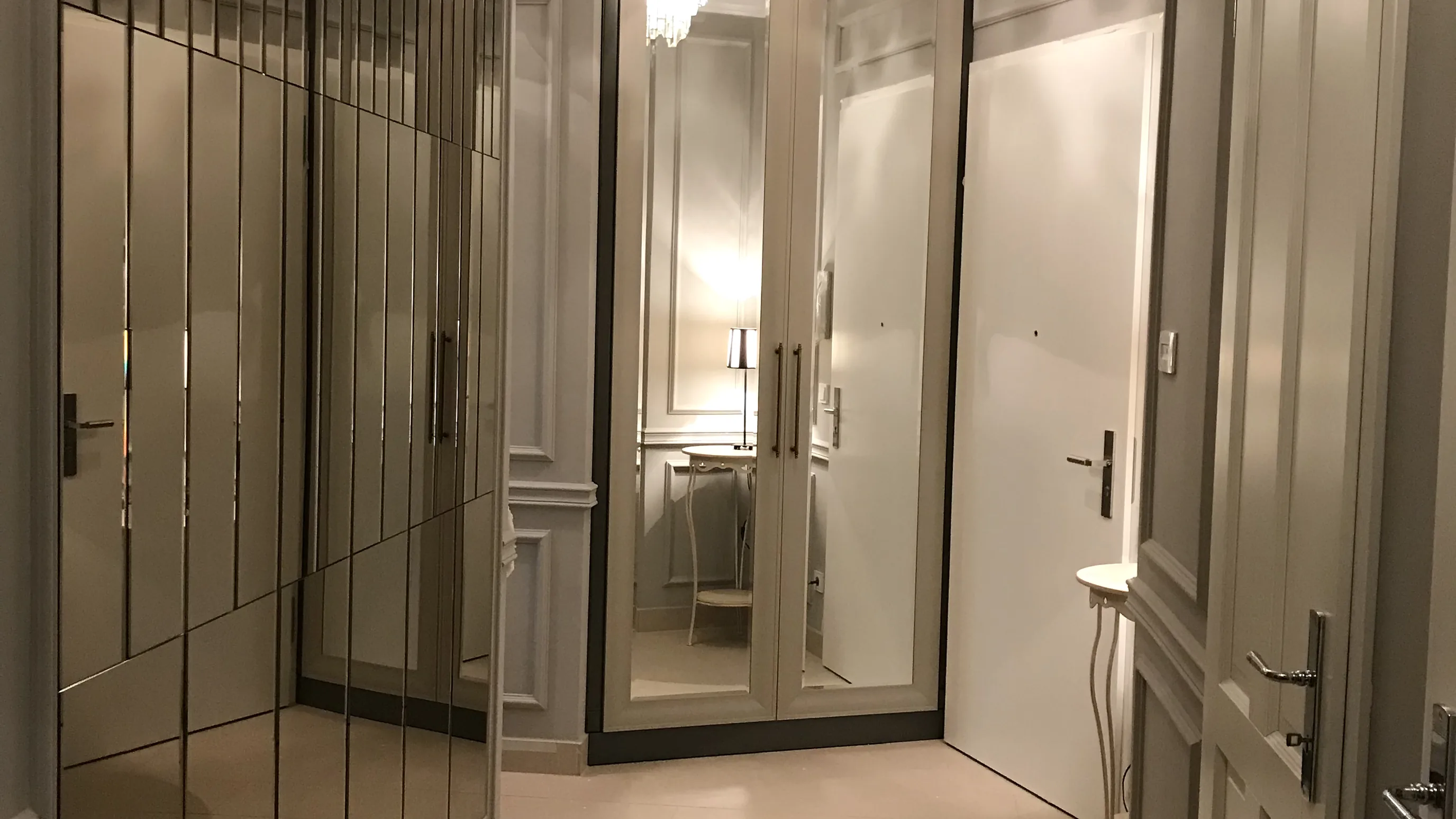 Schmaler Flur mit einem Einbauschrank mit Spiegeltüren in der Ecke, Kristalllüster an der Decke, Konsolentisch und Tür rechts