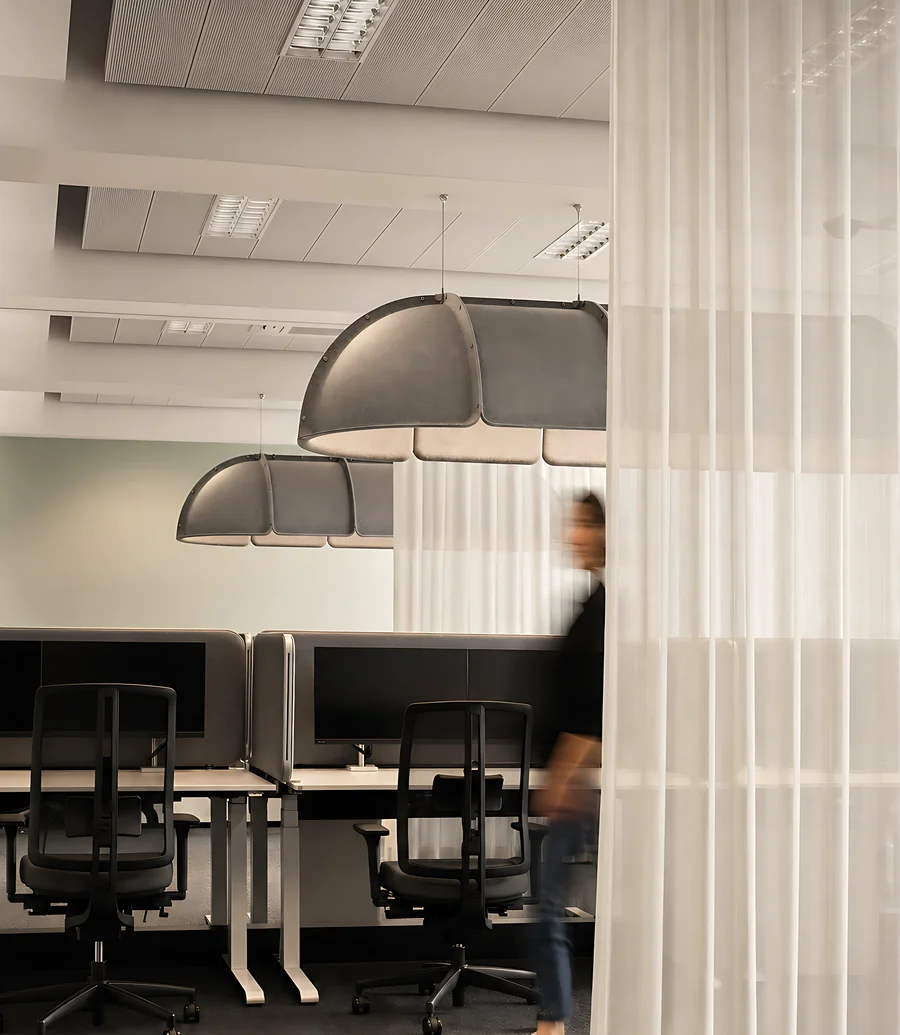 Arbeitssaal hinter einem transparenten Vorhang als Raumteiler, Schreibtische mit Bildschirmen dahinter